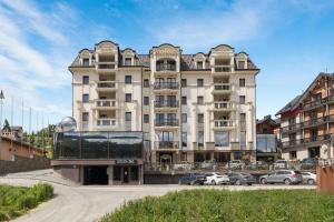 a large building with cars parked in front of it at MARION SPA Hotel & Spa - RENOVATION - Rooms, SPA area, Swimming pool, Reception, Restaurant, Lounge Bar, Hookah bar, Children's room, Parking, SPA and Breakfast included in the price in Bukovel