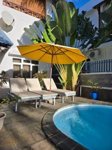 a pool with a yellow umbrella and chairs and a swimming pool at sea view in Pereybere