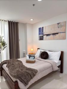 a bedroom with a large bed with a blanket on it at 1BR with Pool at One Pontefino Tower, Batangas City in Batangas City