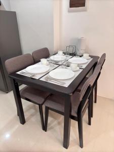 a black table with four chairs and plates on it at 1BR with Pool at One Pontefino Tower, Batangas City in Batangas City