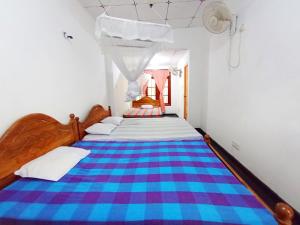 two beds in a room with a blue and white blanket at Villa Agrico and Surf Guest in Weligama