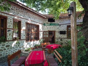 a building with red tables and benches in front of it at Стария Чинар in Melnik +12 photos