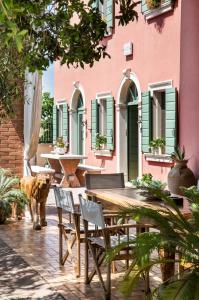 eine Terrasse mit einem Holztisch und Stühlen vor einem rosa Gebäude in der Unterkunft Relais Ca' Maddalena in Villafranca di Verona