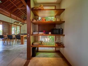 cocina con estanterías de madera y comedor en 3 BR Barani Villa Tanah Lot with Rice Paddy View & Private Pool, en Tanah Lot