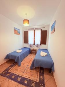 two beds in a room with blue sheets at Casa Joe in San Vito lo Capo