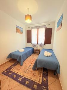two blue beds in a room with a rug at Casa Joe in San Vito lo Capo