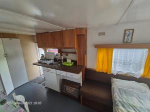 a small kitchen in an rv with a bed at Dom Bursztynek - holender in Junoszyno
