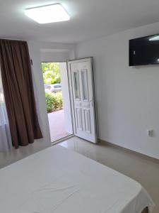 a bedroom with a white bed and a sliding glass door at Cazare Pedro in Mamaia