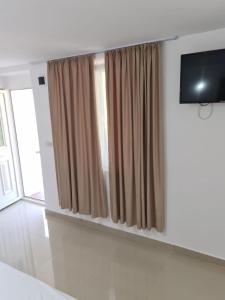 a living room with a television and curtains at Cazare Pedro in Mamaia