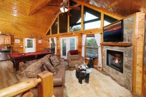 a living room with a large stone fireplace in a log cabin at Edge of Paradise in Pigeon Forge