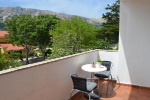 balcone con tavolo, sedie e montagne di Apartments Mili a Baška