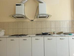 Una cocina con gabinetes blancos y luces sobre la encimera. en MILLIY Hostel, en Jizzax 12 fotos más