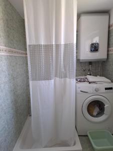 a white shower curtain in a bathroom with a washing machine at Small Nature house Teodora in Novalja