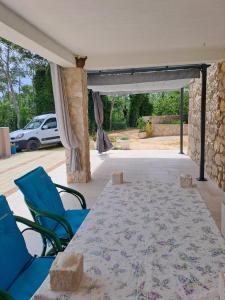 a patio with a table and chairs and a stone wall at Small Nature house Teodora in Novalja