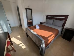 a bedroom with a large bed with an orange blanket at Hotel Arda Bali in Negara