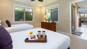 a bedroom with two beds and a table with a picture at SOAK UP THE SUN VILLA Sun-Drenched 3BR KaMilo Home with Golf Course View in Waikoloa +64 photos