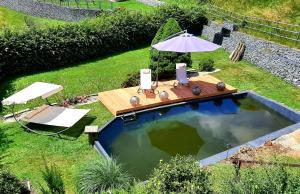 a swimming pool with a table and an umbrella at Mama Roserl in Hauzenberg
