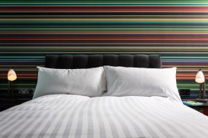 a bed with white pillows in front of a striped wall at Village Hotel Cardiff in Cardiff