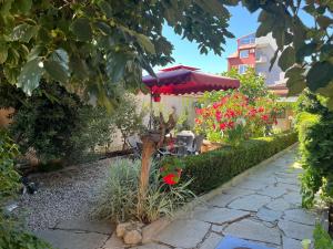 a garden with an umbrella and chairs and flowers at Петкови Лозенец in Lozenets +9 photos