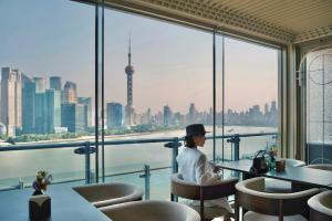 a woman sitting at a table looking out at the city at Banyan Tree Shanghai On the Bund in Shanghai