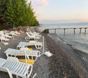 a group of white chairs on a beach near the water at Studio Tamara in Ohrid +10 photos