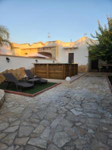 un patio de piedra con 2 sillas y un edificio en Villa Malese, en Porto Cesareo