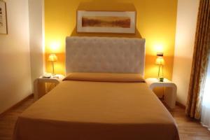 a bedroom with a large bed with two lamps on tables at Hotel Bouza in Ribadeo