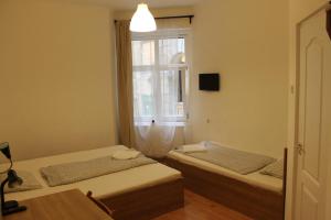 two beds in a room with a window at Fanni Budapest Guesthouse in Budapest