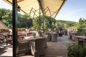 un patio al aire libre con mesas, sillas y árboles en Hotel West en Bratislava