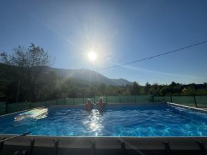 two people in a swimming pool with the sun behind them at Lux apartmani in Bihać