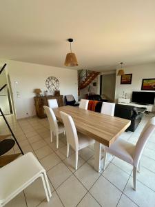 ein Esszimmer mit einem Holztisch und weißen Stühlen in der Unterkunft La Maison Bleue in Saint-Avé