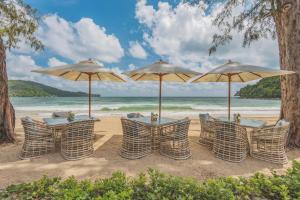 a group of tables and umbrellas on a beach at Twinpalms MontAzure Phuket in Kamala Beach