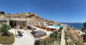 a resort with a pool and chairs and the ocean at Apostolis Windmill in Psarou