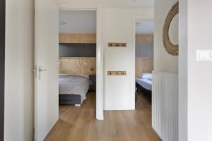 a bedroom with a bed and a mirror at Lodge 't Hert - Nieuwe lodge met vrij uitzicht & omheinde tuin in Putten