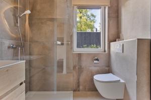 a bathroom with a shower and a toilet and a window at Lodge 't Hert - Nieuwe lodge met vrij uitzicht & omheinde tuin in Putten +20 photos