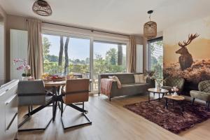 a living room with a couch and a table at Lodge 't Hert - Nieuwe lodge met vrij uitzicht & omheinde tuin in Putten