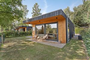 a small wooden house with a glass door at Lodge 't Hert - Nieuwe lodge met vrij uitzicht & omheinde tuin in Putten