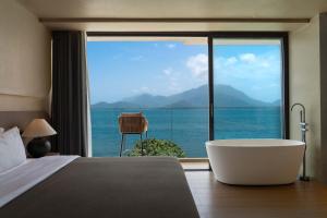 a bedroom with a tub and a view of the ocean at 深圳较场尾东海岸海景民宿 in Dapeng