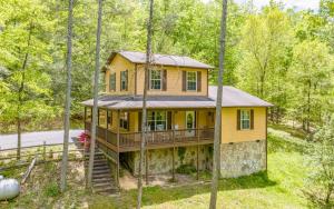 セバービルにあるMountain Dreams 1430 Hot Tub Fire Pit Arcade Gameの森の中の黄色い家