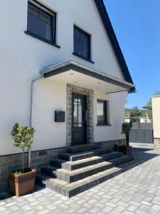 a white house with stairs and a black door at Ferienhaus AhrIdylle in Bad Neuenahr-Ahrweiler