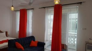 a bedroom with red curtains and a couch and a bed at Nestabs Homes in Mtwapa