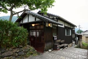 una pequeña casa negra con un banco delante en 鞆猫庵 Tomo Nyahn, en Fukuyama