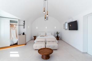 a room with a bed and a table and a tv at Oikos Santorini Living Concept in Fira