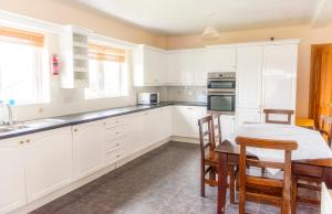 a kitchen with white cabinets and a table and chairs at Duncarbury Heights - 4 Bedroom Detached House in Tullaghan