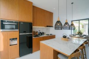 a kitchen with wooden cabinets and a counter top at Modern 3BR Private Pool Villa 5-min Beach in Canggu