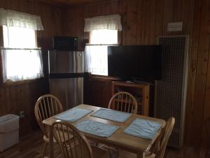a dining room with a table with chairs and a television at adoba® hotel Naubinway in Naubinway +16 photos