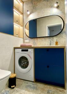 a bathroom with a washing machine and a mirror at Apartament Gruszowe Sady Nowaka 6 in Olsztyn