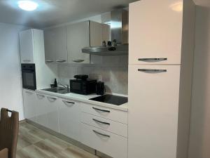 a kitchen with white cabinets and a black microwave at Apartman Marina Vrsi in Vrsi