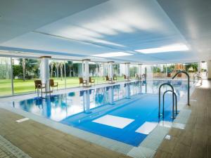 a large pool with chairs and tables in a building at Hotel Monarque Fuengirola Park in Fuengirola