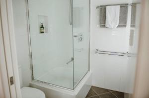 a bathroom with a glass shower with a toilet at Surfside Cudmirrah Beach in Berrara